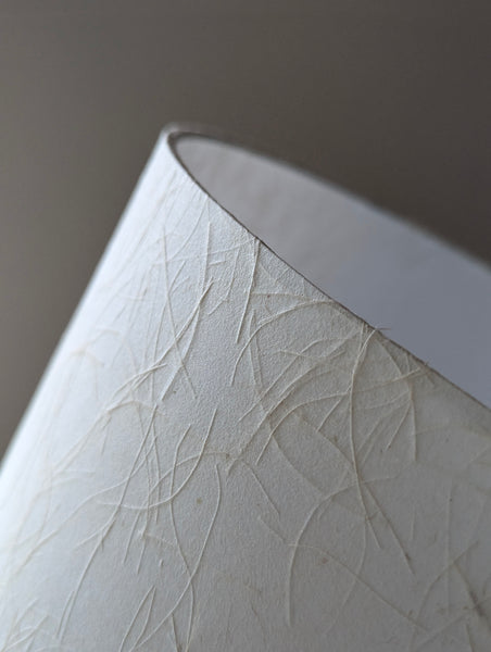 close up of a textured paper lamp shade in cream colorway 