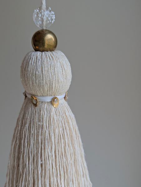 snowy white tassel in a natural cotton color with brass accents and a handblown glass bead