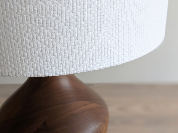 Close-up of a white textured lampshade in Bright White Crosshatch fabric against a soft gray background