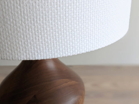 Close-up of a white textured lampshade in Bright White Crosshatch fabric against a soft gray background