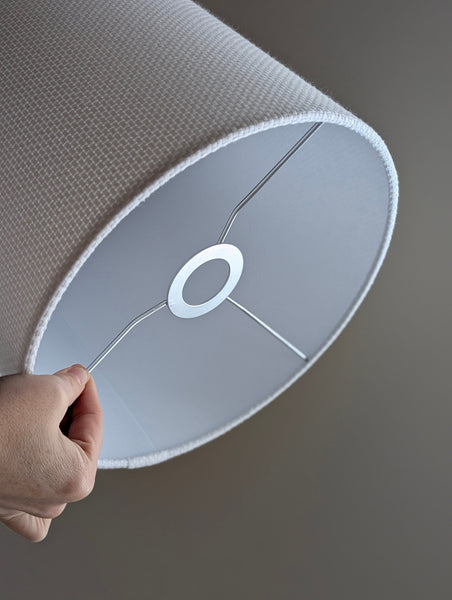 Close-up of a white textured lampshade in Bright White Crosshatch fabric against a soft gray background