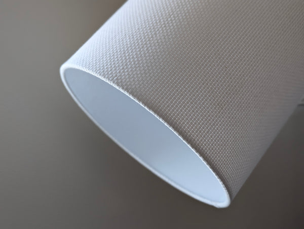 Close-up of a white textured lampshade in Bright White Crosshatch fabric against a soft gray background