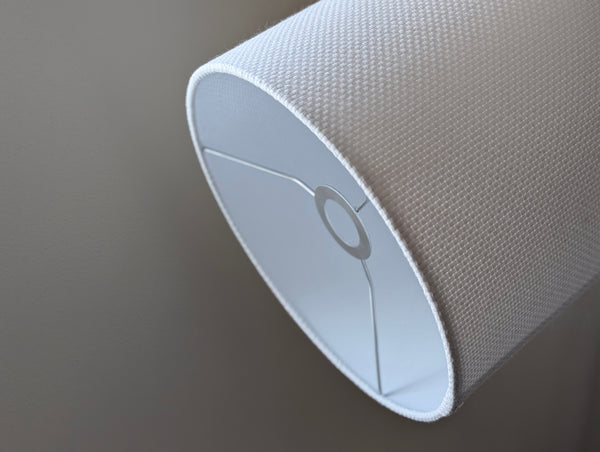 Close-up of a white textured lampshade in Bright White Crosshatch fabric against a soft gray background