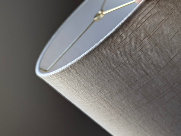 Close-up of a drum lampshade made of white linen fabric with spider washer hardware