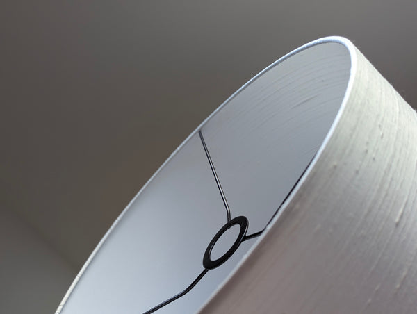 Close-up of a white textured lampshade with euro fitter hardware, set against a neutral gray background.
