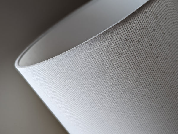 close up of striped and polka dotted lamp shade in white-on-white pattern