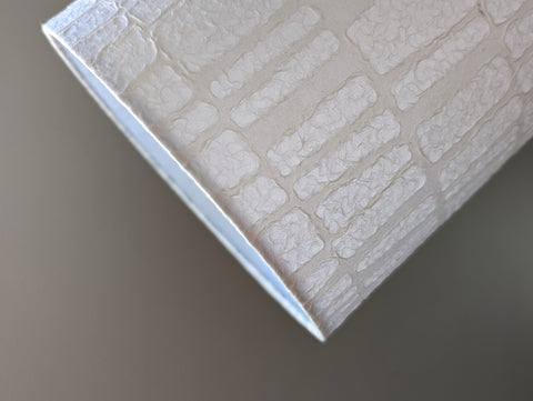 close up of the wrapped edge of a drum lampshade made of white textured paper