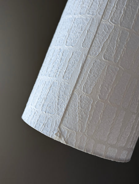 Close-up of the back seam of a textured white paper lamp shade with a triangle stitch detail at the bottom