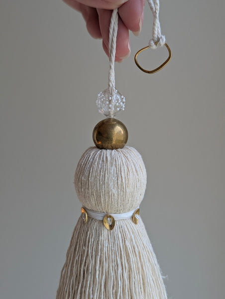 snowy white tassel in a natural cotton color with brass accents and a handblown glass bead