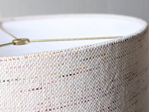 close up image of edge detail of handmade lamp shade made from handwoven confetti fabric in ivory with flecks of color
