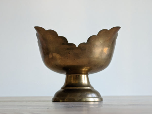 side view of a vintage brass candle with petalled edge