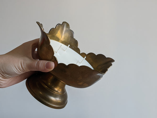 vintage brass candle with petalled, scalloped edge being held in the light