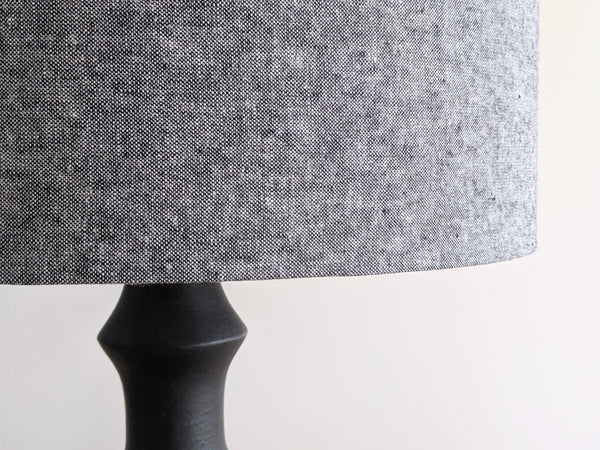 a black and white fabric lampshade that appears grey is on a black table lamp