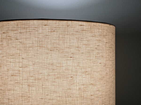 Close up of blush linen lamp shade lit up at night to show the texture of the linen fabric.