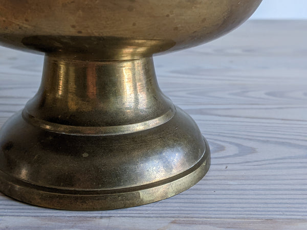 close up shot of the base of a brass pedestal candle
