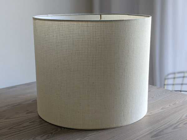 Handmade lamp shade in Grid Ecru fabric sitting on wooden table