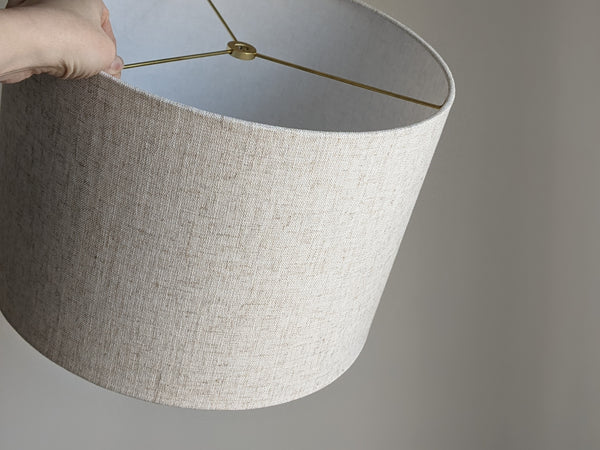 hand holding handmade lampshade in Calacatta Gold Flax fabric with brass hardware
