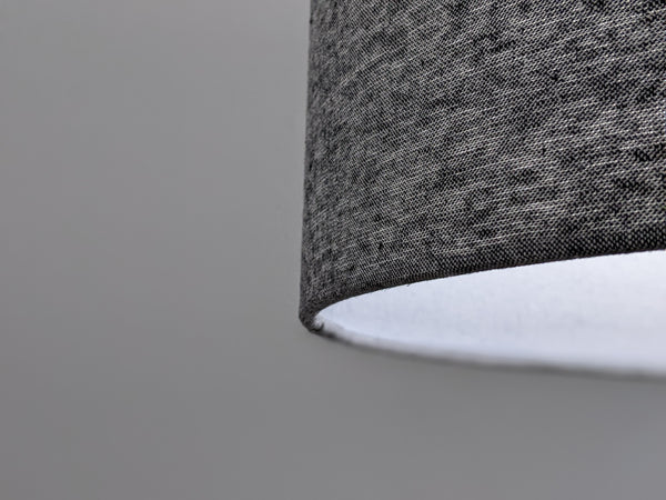 close up of black and white fabric lamp shade while the lamp is lit and the light from the bulb is shining through the fabric