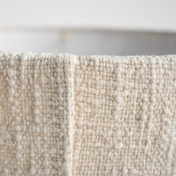 A close up showing the back seam on the handwoven boucle table lamp. It emphasizes the nubby texture and cream color.