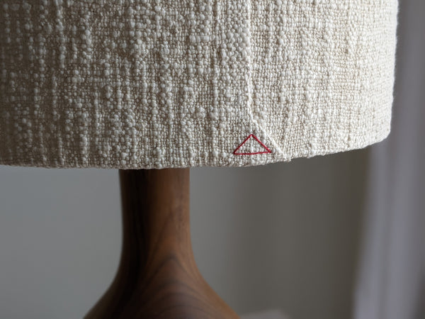 close up of red triangle stitch detail on bottom of back seam on a cream boucle lamp shade