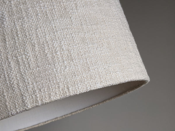 close up of bottom edge detail on a cream colored, handwoven fabric lamp shade