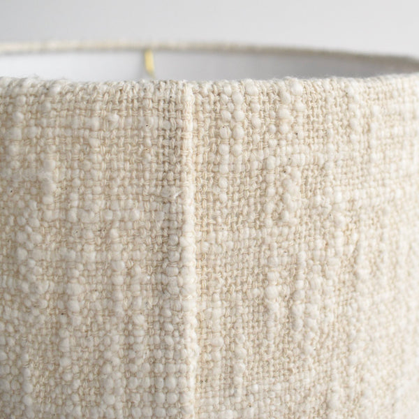 A close up showing the back seam on the handwoven boucle table lamp. It emphasizes the nubby texture and cream color.