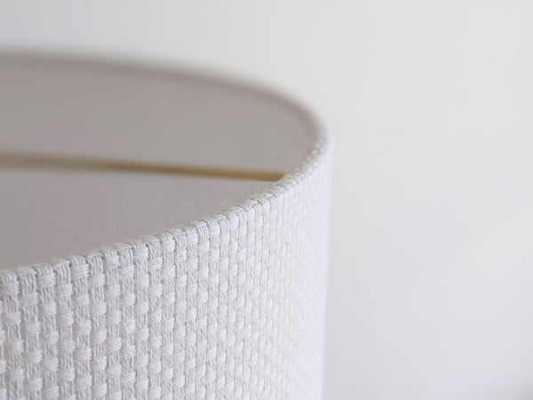 close up image of bright white crosshatch fabric on a drum shade with brass hardware