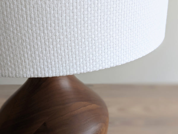 close up shot of white crosshatch fabric lamp shade on a walnut table lamp